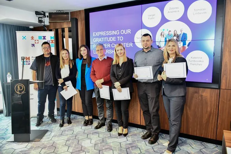 A group of attendees holding certificates in front of the chapter's slide of thanks