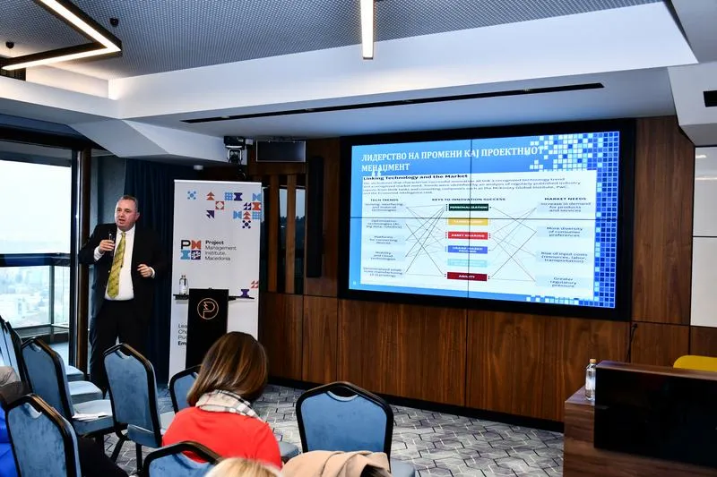A speaker in the hall beside a Macedonian-language slide on leadership in project management
