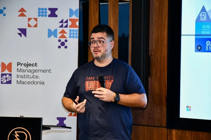 A speaker in front of the wall carrying the Project Management Institute Macedonia mark and pattern