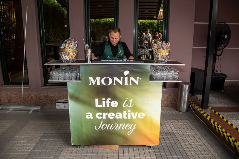 A bartender setting up the MONIN bar in the courtyard before the lunch break